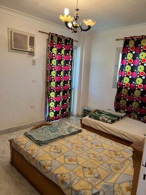 Un dormitorio con dos camas, una araña y cortinas con estampado de frutas.