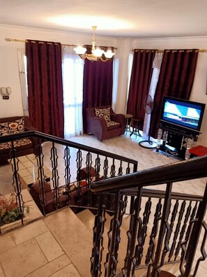 Una sala de estar con un sofá, una televisión y una escalera.