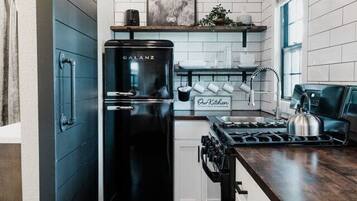 A modern kitchen with a black refrigerator, a stove, and a wooden countertop.