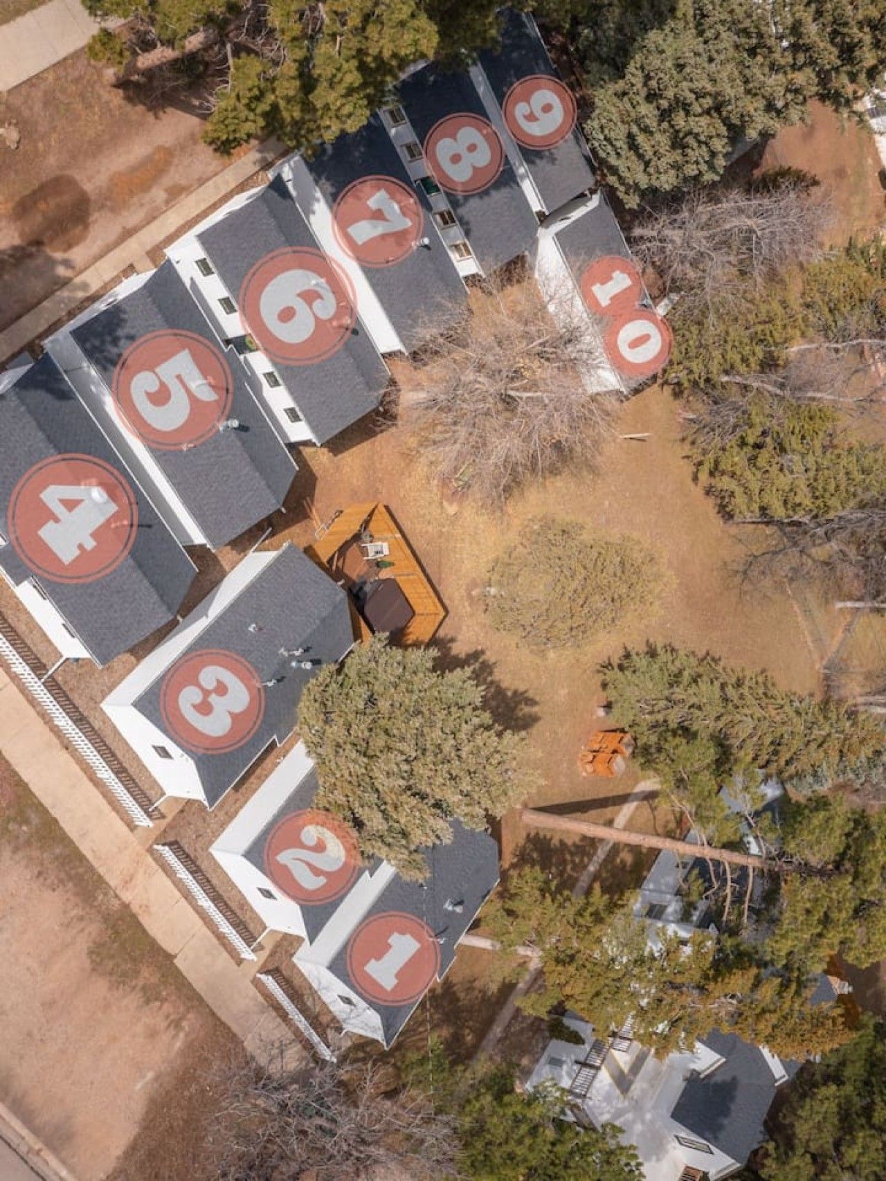 Luchtbeeld van een parkeerplaats met genummerde parkeerplaatsen, omringd door bomen en een bouwmachine.