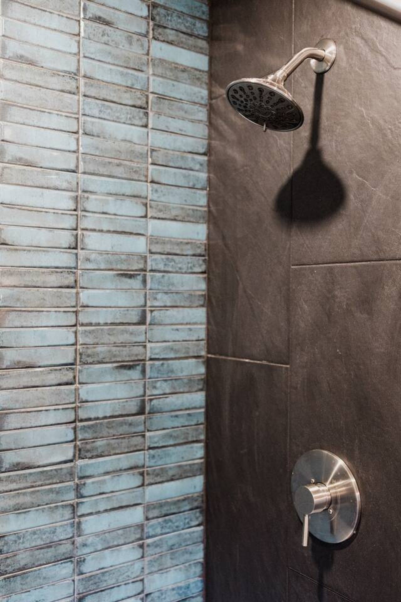 Een douche met een handdouche en een bedieningsknop aan de muur.