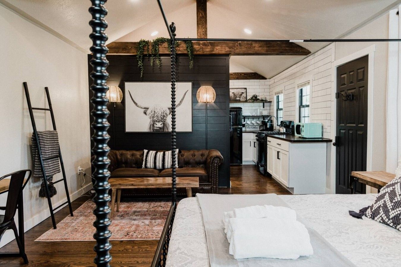 A modern interior with a bed, a sofa, a dining area, and a kitchen.