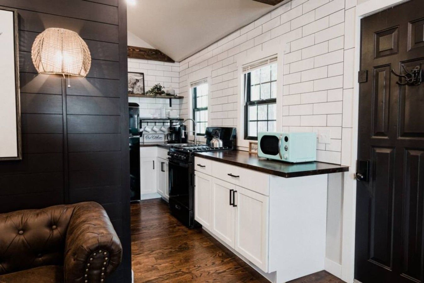 Una cocina con gabinetes blancos, una estufa negra y un microondas de estilo vintage.