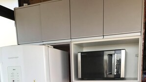 A compact kitchen with a white refrigerator, a microwave on a shelf, and a coffee maker on the countertop. - Chalé Mirante Reservations only through the website ChalesTemporada.com (Alexânia)