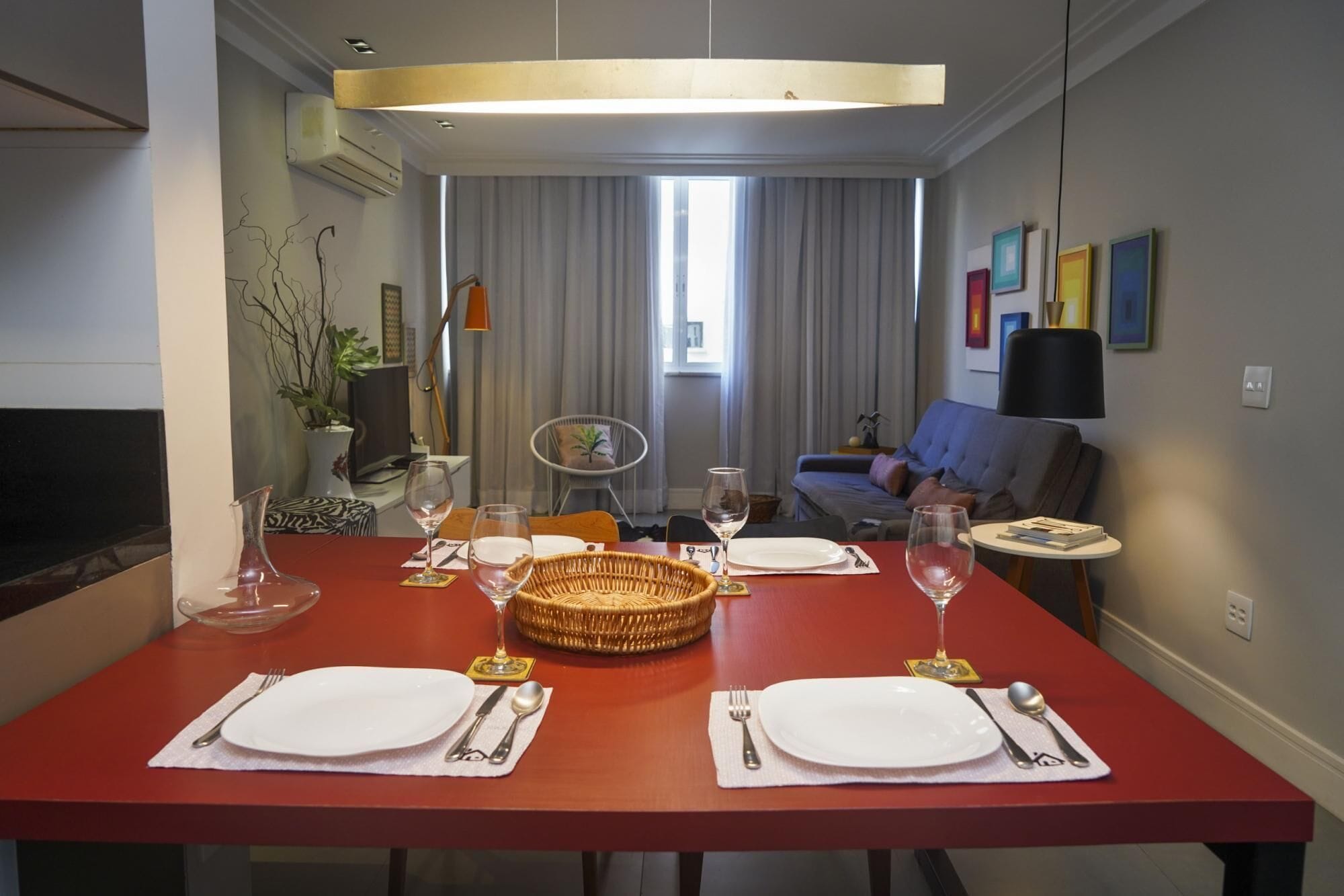 A dining area with a red table set for four, including plates, cutlery, and wine glasses.