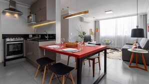 A modern kitchen with a central island, a dining area with a red table, and a living room with a sofa and a lamp. - Modern in Ipanema Great for Families Re406 Z2 (Rio de Janeiro)