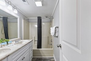 A bathroom with a bathtub, a shower, a sink with toiletries, and a mirror. - Beachfront 1BR Condo in Myrtle Beach (Myrtle Beach)