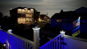 A residential area at night with houses, a visible American flag, and a street with cars.