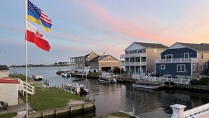 A waterfront property with a dock, boats, and a flagpole with multiple flags.