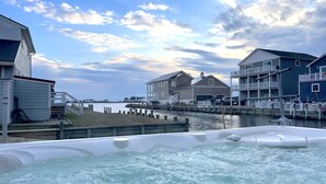 A waterfront property with a hot tub, a dock, and a view of the water and buildings.