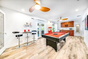 Eine moderne Küche mit Holzausstattung, einem Billardtisch und einem an der Wand befestigten Fahrrad.
