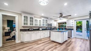 A spacious kitchen with white cabinetry, a large island, and a view of the outdoors. - NEW! 5 BED/5 MIN TO BEACH/HTD POOL/HOT TUB/BAR (Oakland Park)