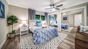 A bedroom with a bed, nightstands, a ceiling fan, a potted plant, and a view of the outdoors. - NEW! 5 BED/5 MIN TO BEACH/HTD POOL/HOT TUB/BAR (Oakland Park)
