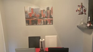 Un coin repas avec une table dressée pour quatre personnes, un ventilateur de plafond et un tableau accroché au mur.