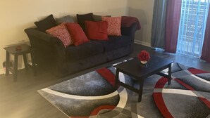 Un salon avec un canapé de couleur sombre, une table basse et un tapis à motifs. Trois tableaux encadrés sont accrochés au mur.