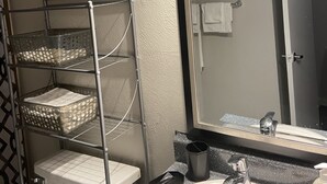Une salle de bain avec des toilettes, un lavabo avec un miroir et une étagère avec des paniers.