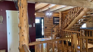A wooden interior with a staircase, a door, and a hanging light fixture.