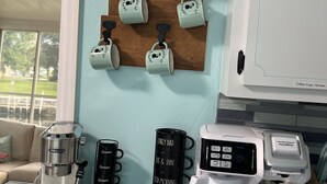 A kitchen with a coffee maker, a grinder, and a coffee cup rack. - Weeki Wachee Gardens on the Canal (Spring Hill)
