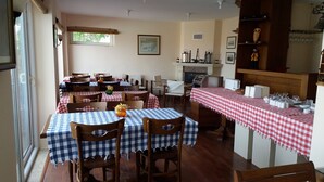A dining area with checkered tablecloths, wooden chairs, and a buffet counter with food items. - DM Residence Butik Otel (Datça)