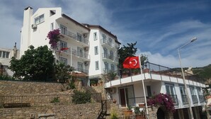 A multi-story hotel with balconies, stone walls, and potted plants. - DM Residence Butik Otel (Datça)