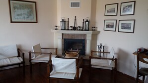 A traditional living room with a fireplace, framed pictures on the wall, and a wooden floor. - DM Residence Butik Otel (Datça)