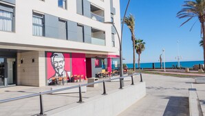 A modern building with a flat facade, outdoor seating area, and a view of the sea. - Cubo's Sea View Pacifico Street & Free Parking / free wifi / air conditioning (Málaga)