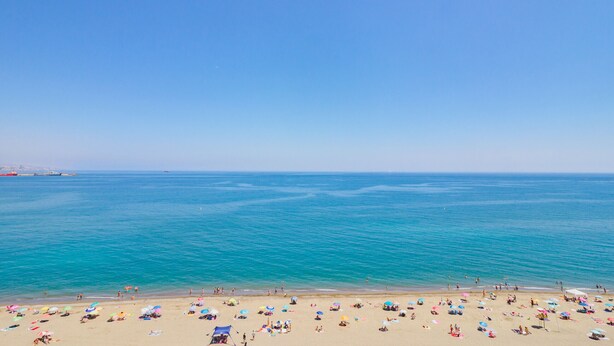 A beach with a clear blue sky, calm sea, and numerous colorful umbrellas. - Cubo's Sea View Pacifico Street & Free Parking / free wifi / air conditioning (Málaga)