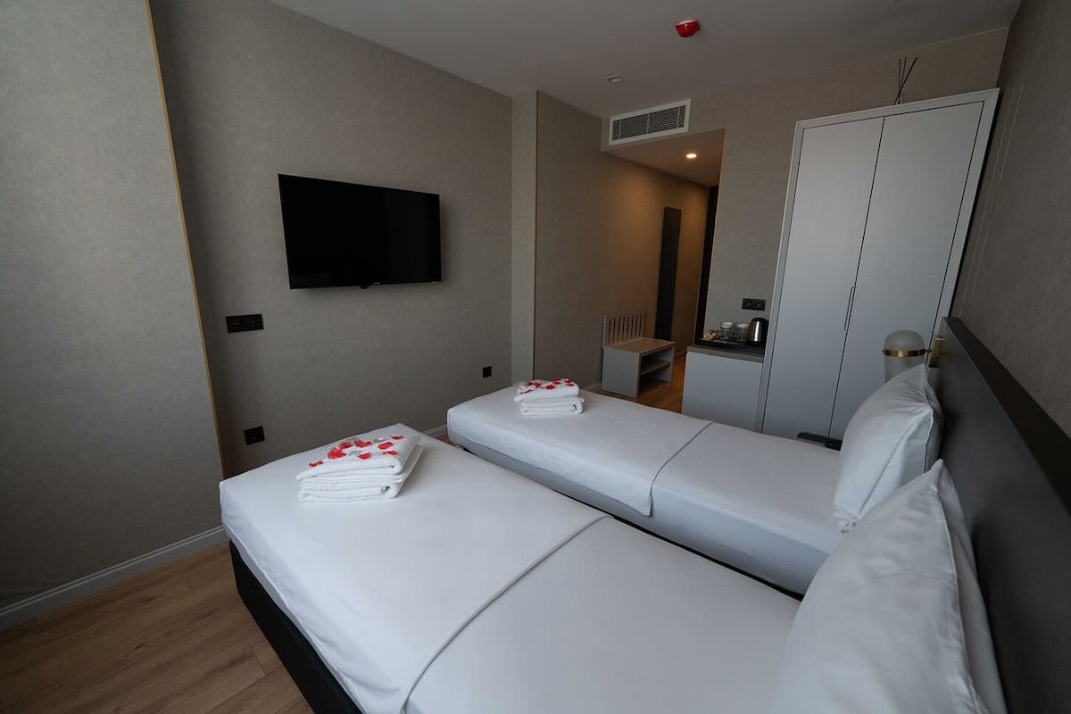 Ein Hotelzimmer mit zwei Betten, einem Fernseher, einem Kleiderschrank und einer Küchenzeile.