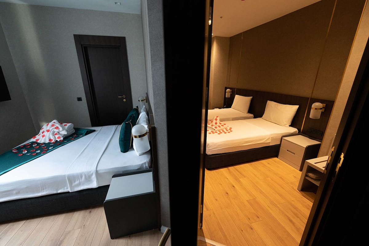 Ein modernes Hotelzimmer mit zwei Betten, einem kleinen Schreibtisch und einem Kleiderschrank.