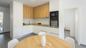 Une cuisine moderne avec des armoires blanches, un plan de travail en bois et un four encastré.
