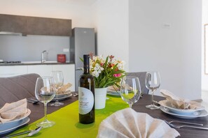A dining table set with plates, glasses, a bottle of wine, and a vase of flowers.