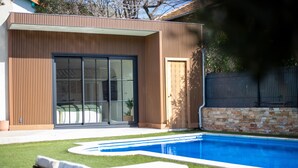 Ein modernes Haus mit Schwimmbad, überdachter Terrasse und einer Steinsäule.