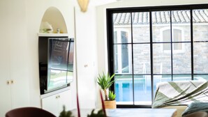 Ein Essbereich mit Holztisch, Stühlen, hängenden Pendelleuchten, einem Topfpflanzen und Blick auf einen Pool durch große Fenster.