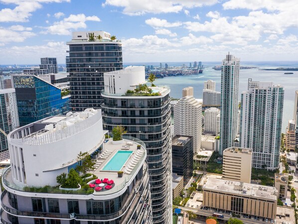 A high-rise building with a rooftop pool and a view of the city skyline and water.