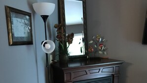 Una habitación de esquina con chimenea de madera oscura, un espejo enmarco, una lámpara de pared y una pequeña figura de oso.