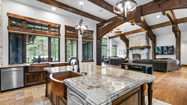 A spacious kitchen with a large island, wooden beams, and a stone countertop. - Luxury Sunriver Estate | 5 Kings + Bunk Rm | Huge Spa & Arcade | Chef's Kitchen (Sunriver)