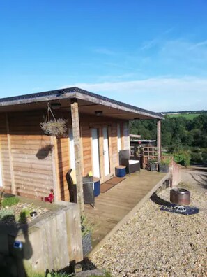 A wooden cabin with a porch, a small garden area, and a gravel path leading to the entrance. - Peaceful Cabin in Skegby -sleeps2- Fire Pit (Sutton-in-Ashfield)