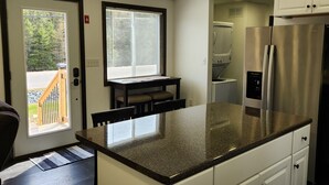 Een moderne keuken met witte kasten, een roestvrijstalen koelkast en een groot eiland.