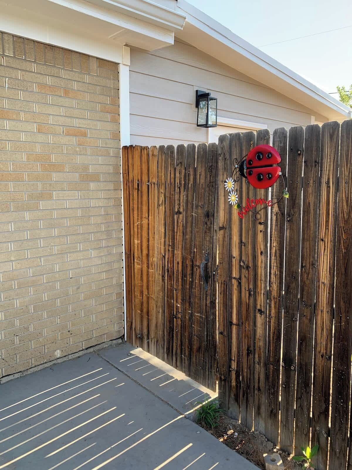 A wooden fence with a decorative ladybug ornament and a small garden area.