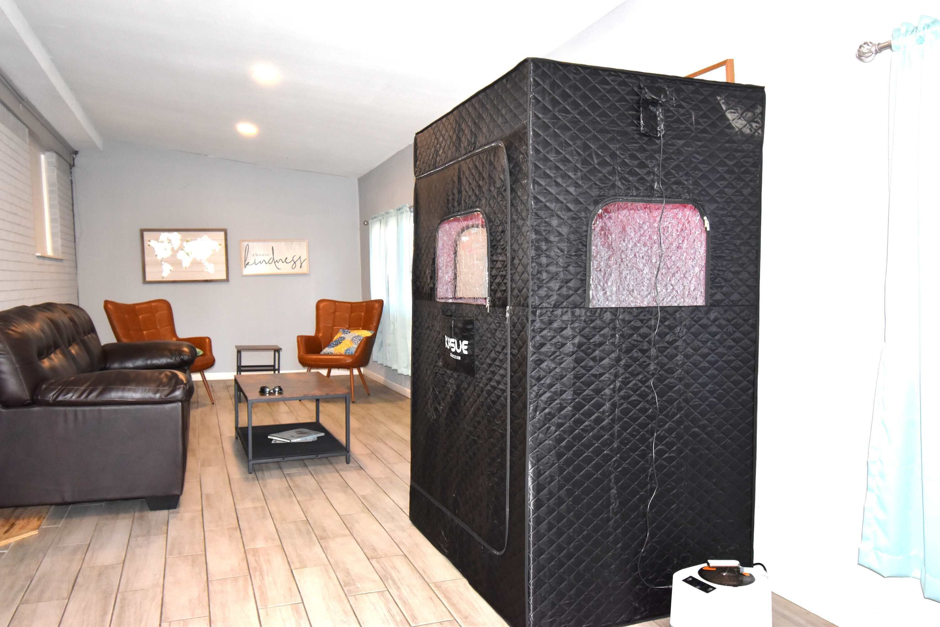 Una sala moderna con un separador negro, un sofá de cuero y dos sillones.