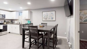 A modern kitchen with white cabinets, a dining table with chairs, a microwave, and a coffee maker. - Great Lower Unit with Spacious Yard and Sunroom (Denver)