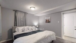 A bedroom with a bed, a nightstand, a lamp, a door, and a wall with a picture. - Great Lower Unit with Spacious Yard and Sunroom (Denver)