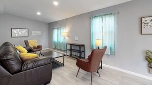 A modern living room with a leather sofa, a brown armchair, a coffee table, and a side table with lamps. - Great Lower Unit with Spacious Yard and Sunroom (Denver)