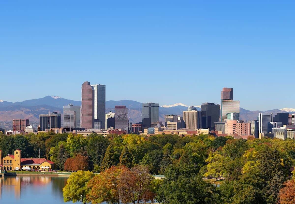 A city skyline with modern buildings and a lake in the foreground.