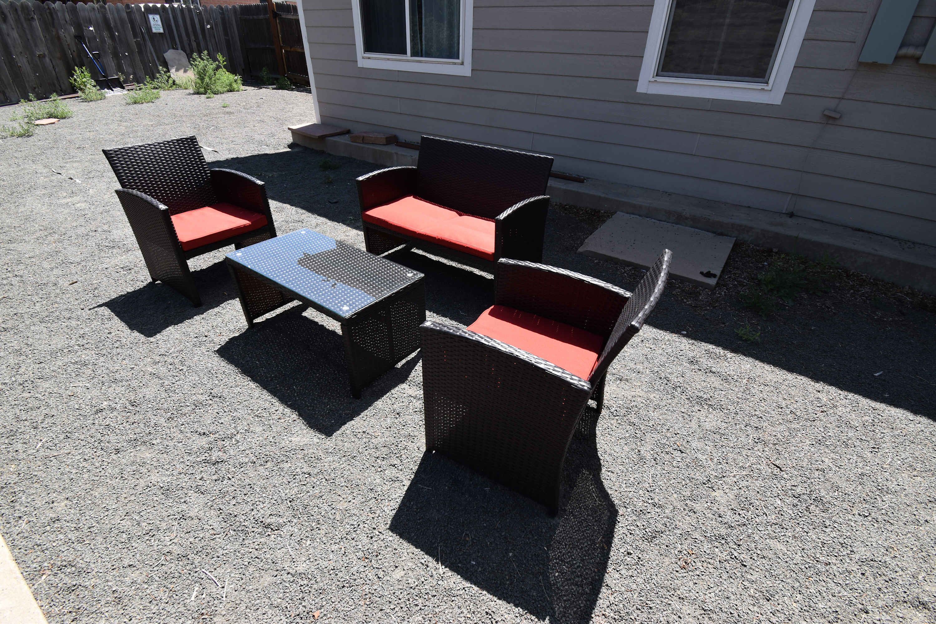 Un patio al aire libre con mobiliario de mimbre y una pequeña mesa.