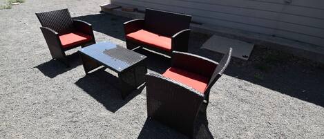 Un patio al aire libre con mobiliario de mimbre y una pequeña mesa.