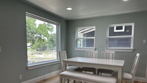 A dining area with a white table and chairs, large windows, and a view of greenery outside. - Waterfront Property on PK - 7 miles away from Rocker B baseball facility  (Graford)