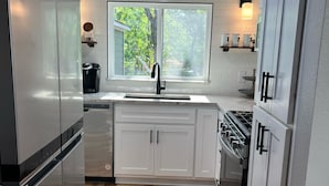 A modern kitchen with white cabinets, a stainless steel refrigerator, a built-in oven, and a window providing natural light. - Waterfront Property on PK - 7 miles away from Rocker B baseball facility  (Graford)