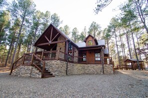 A log cabin with a stone foundation, wooden exterior, and a staircase leading to a deck.