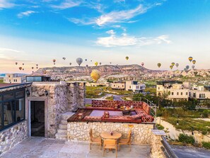 A rooftop terrace with stone walls, a dining table, and chairs. - Ala Stone Hotel (Nevsehir)
